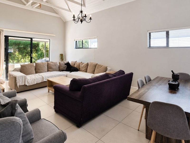 Spacious open-plan living and dining area featuring vaulted ceilings with exposed rafters, tiled flooring, and large sliding glass doors providing natural light.