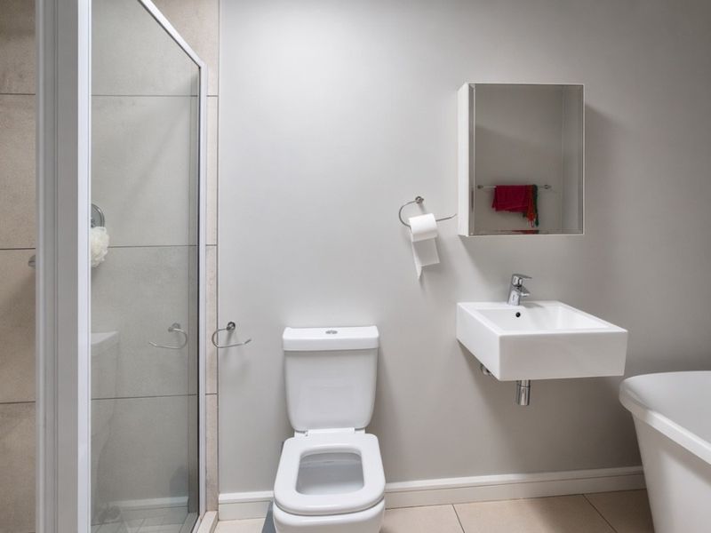 Modern bathroom featuring a glass-enclosed shower, wall-mounted basin, freestanding bathtub, and neutral tiled finishes.