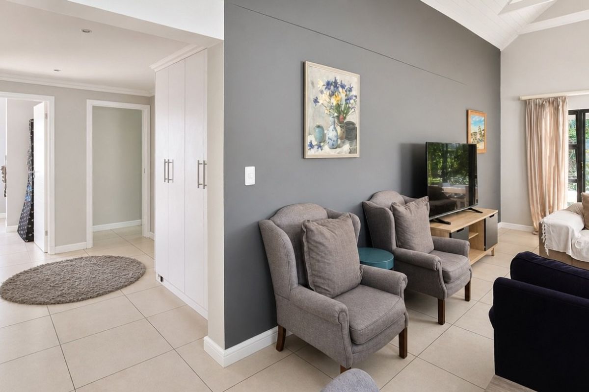 A bright living room featuring tiled flooring, a vaulted ceiling, recessed lighting, and built-in storage cabinetry, creating a comfortable and functional living space.