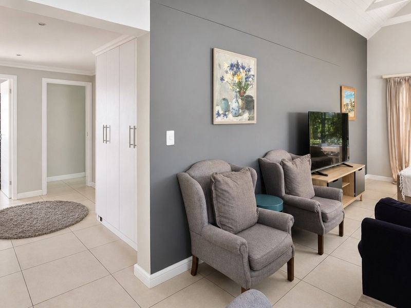A bright living room featuring tiled flooring, a vaulted ceiling, recessed lighting, and built-in storage cabinetry, creating a comfortable and functional living space.