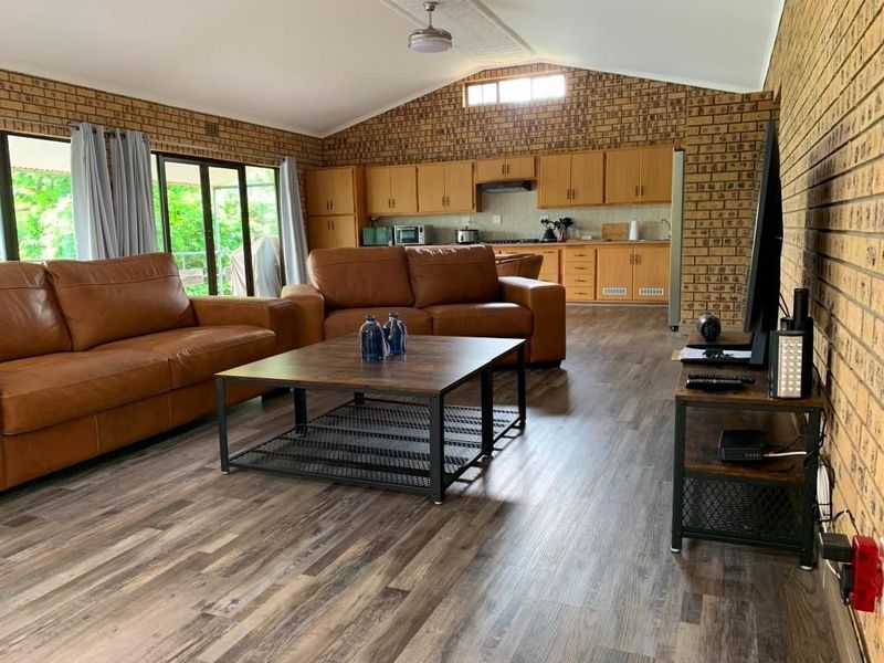 Spacious open-plan living area featuring exposed brick walls, vaulted ceilings, and a functional kitchen with wooden cabinetry and integrated appliances.