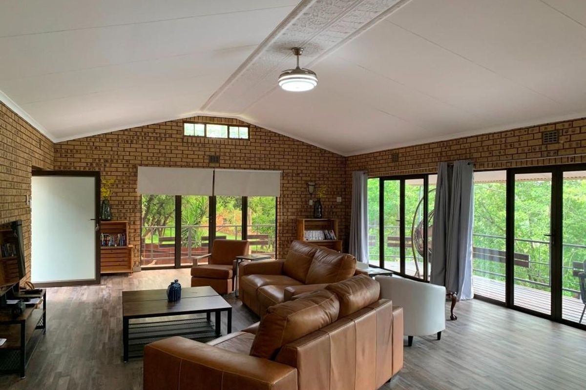 Spacious living area featuring exposed brick walls, vaulted ceilings with a central fan, and large glass sliding doors opening onto a deck.