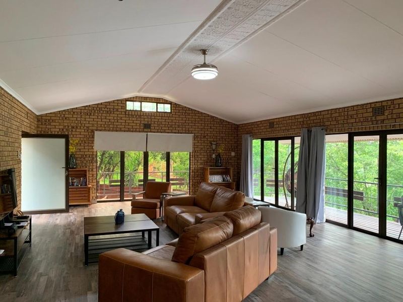 Spacious living area featuring exposed brick walls, vaulted ceilings with a central fan, and large glass sliding doors opening onto a deck.