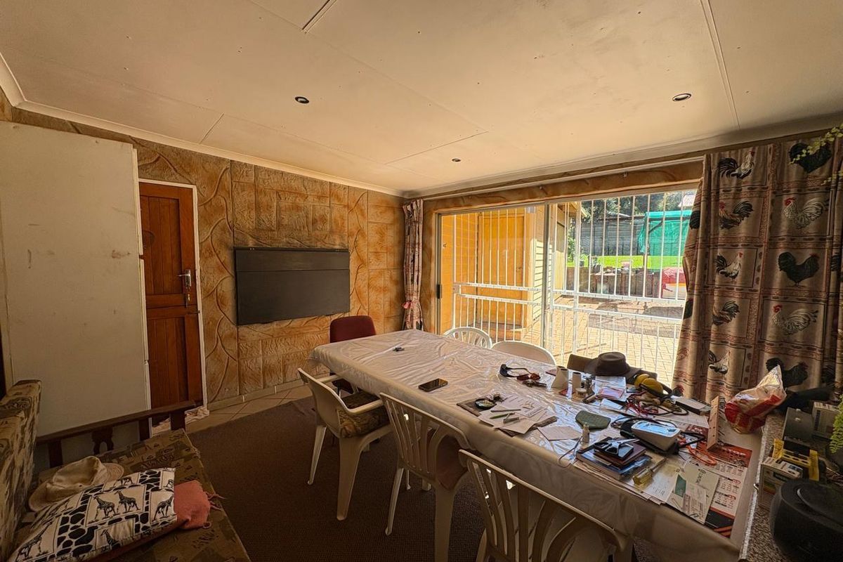A multi-purpose living and dining area featuring sliding glass doors with security gates, leading to an outdoor space.