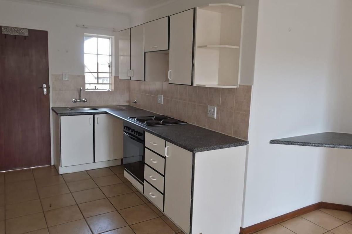 A functional kitchen featuring built-in cabinetry, laminate countertops, a built-in oven with hob, and ceramic tile flooring.