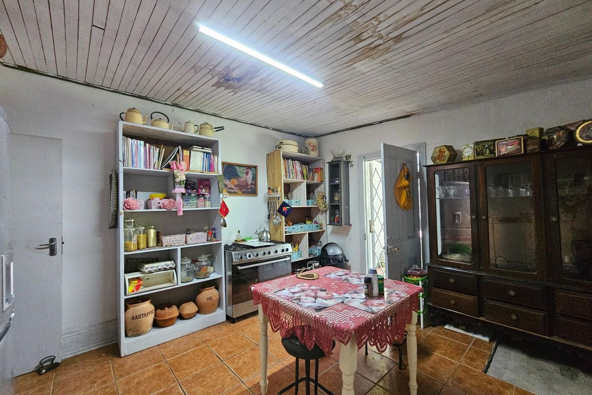 A kitchen area featuring tiled flooring and a timber-paneled ceiling showing signs of water damage and wear.