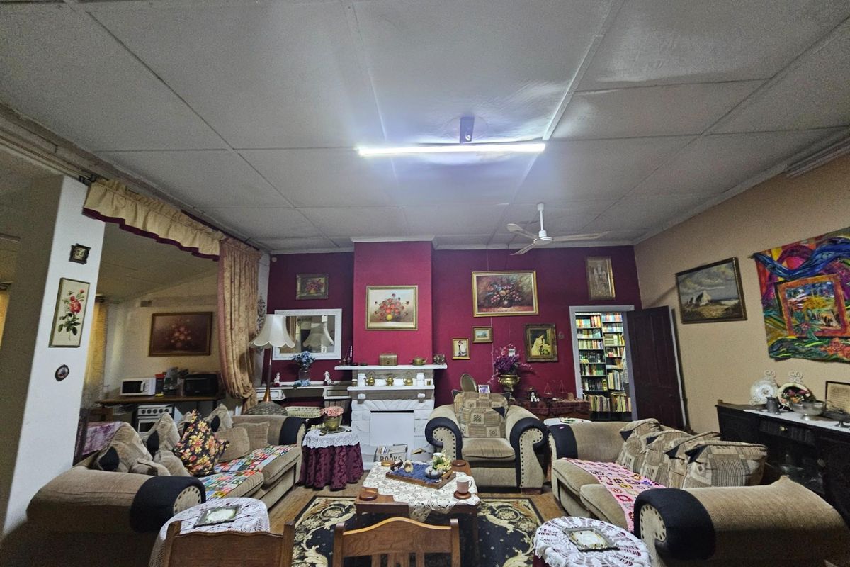 Spacious living room featuring a central fireplace, tiled ceiling, and an open-plan layout connecting to an adjacent kitchen area.