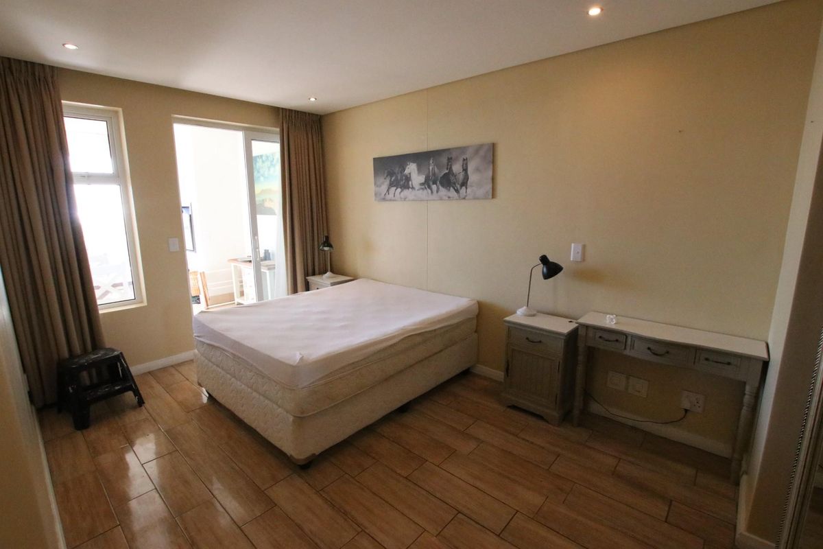 A bedroom featuring wood-look tile flooring, recessed ceiling lighting, and a sliding glass door providing access to an outdoor balcony area.