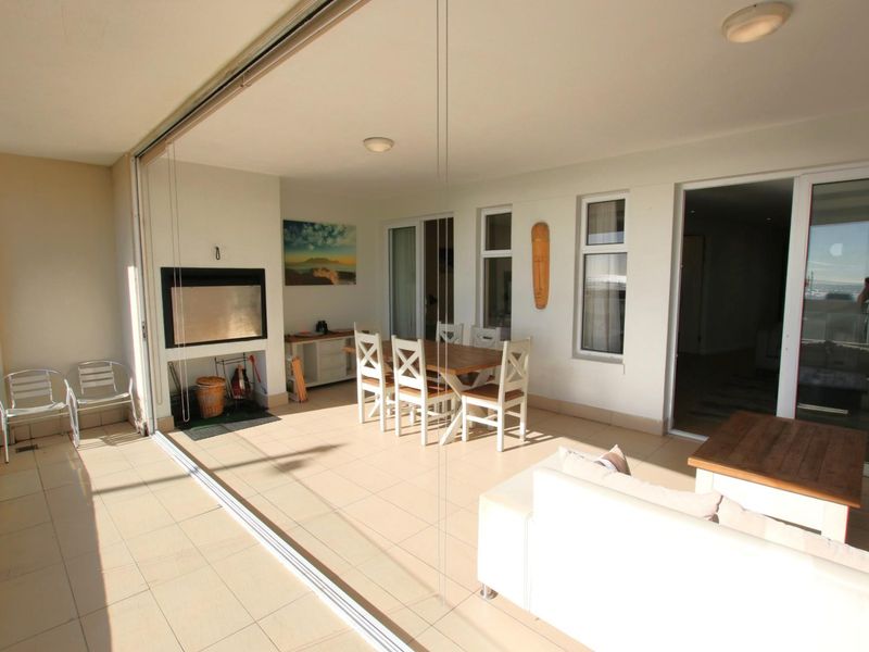 Spacious covered balcony featuring tiled flooring, a built-in fireplace, and large sliding glass doors, offering a seamless transition to the interior living space.