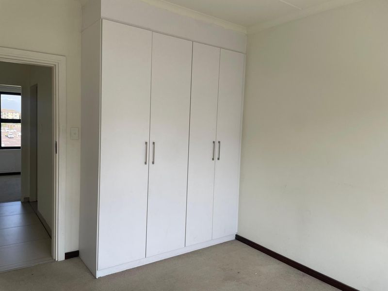 A bedroom featuring built-in white cabinetry with modern handles and neutral carpeting, providing functional storage space.