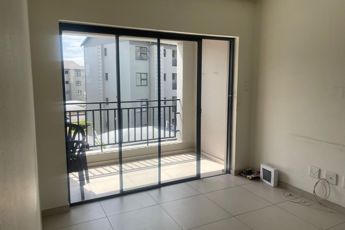 Living area featuring large sliding glass doors leading to a private balcony with tiled flooring and neutral wall finishes.