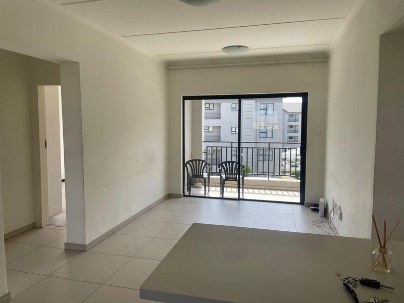 An open-plan living area featuring tiled flooring and a sliding glass door leading to a private balcony.