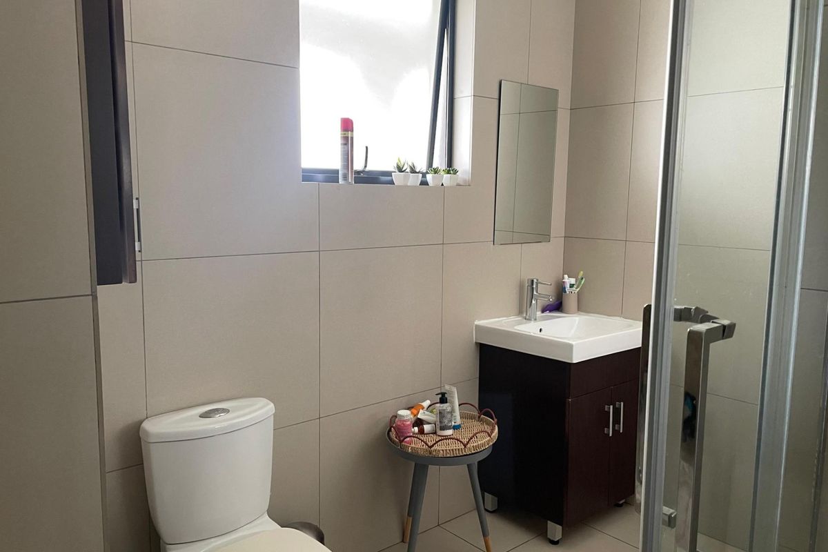 A modern bathroom featuring large-format wall tiles, a vanity with a basin, a toilet, and a glass-enclosed shower.
