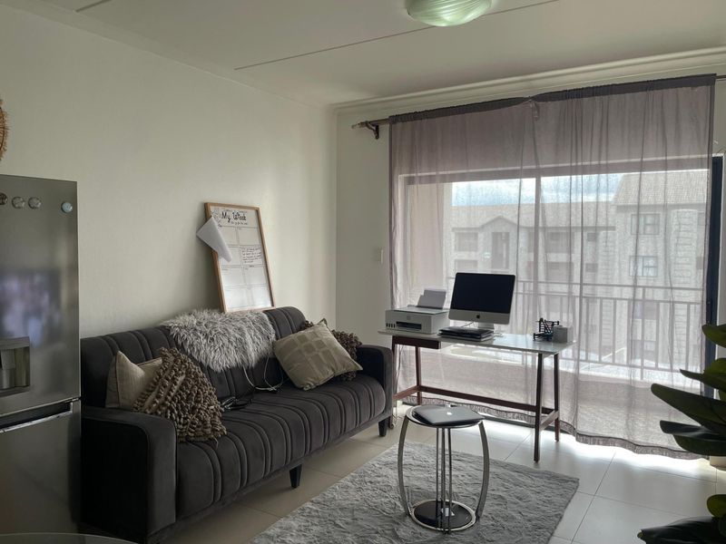 A functional living area featuring tiled flooring and large sliding glass doors that provide access to a balcony.