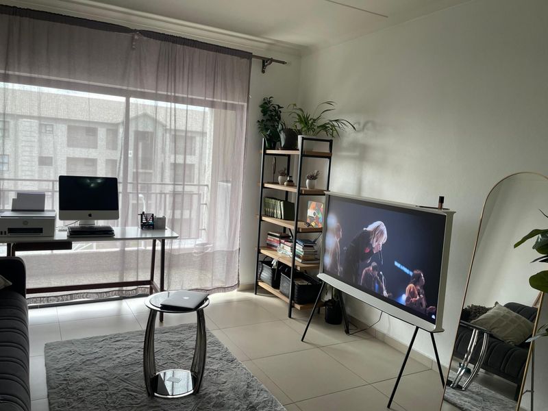 A bright living area featuring large sliding glass doors leading to a balcony, tiled flooring, and neutral wall finishes.