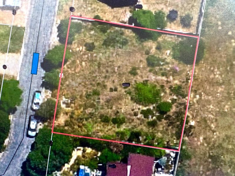 An aerial view of a vacant residential plot, highlighting the property boundaries and surrounding landscape.