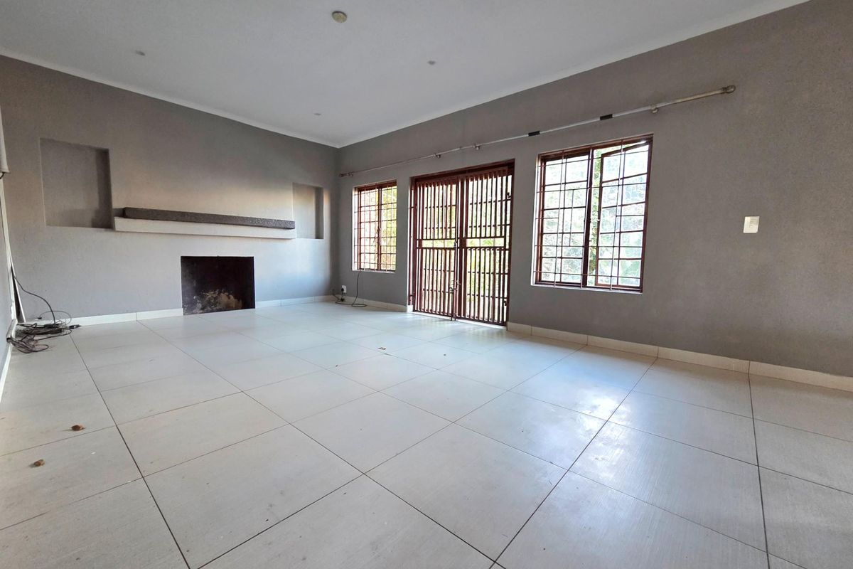 Spacious living room featuring large ceramic floor tiles, a built-in fireplace, and security gates leading to the exterior.