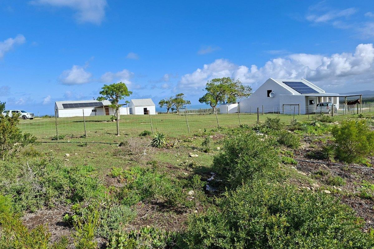 A wide-angle view of the farm property featuring multiple white buildings with solar panel installations, set within a spacious, open landscape.