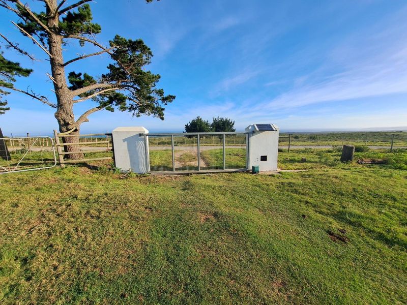 A secure gated entrance to the farm property, featuring a metal gate with solar-powered infrastructure and surrounding wire fencing.