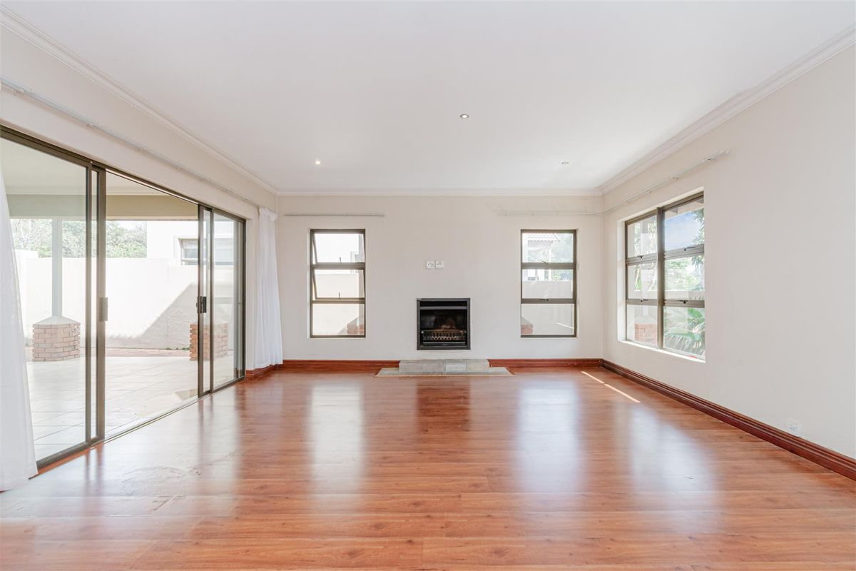 Spacious, empty living room featuring laminate flooring, a built-in fireplace, and large sliding glass doors providing access to the outdoor patio area.