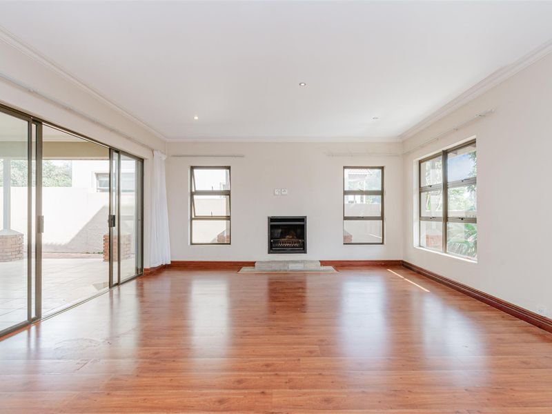 Spacious, empty living room featuring laminate flooring, a built-in fireplace, and large sliding glass doors providing access to the outdoor patio area.