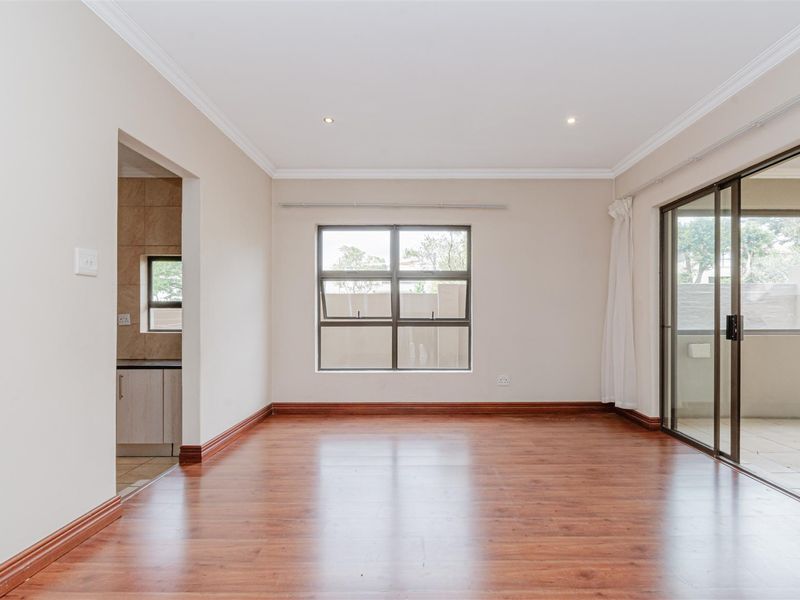 A bright and spacious living area featuring warm laminate flooring, recessed lighting, and large sliding glass doors that provide access to an outdoor space.