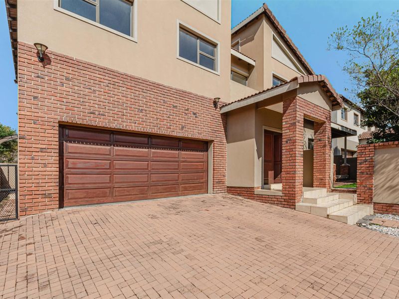 Front elevation of a multi-story house featuring a brick facade, paved driveway, and a covered entrance porch with integrated garage access.