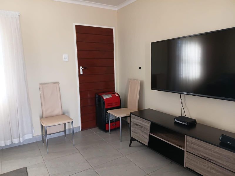 A living room featuring neutral wall tones, tiled flooring, and a timber door, providing a functional and well-maintained space.