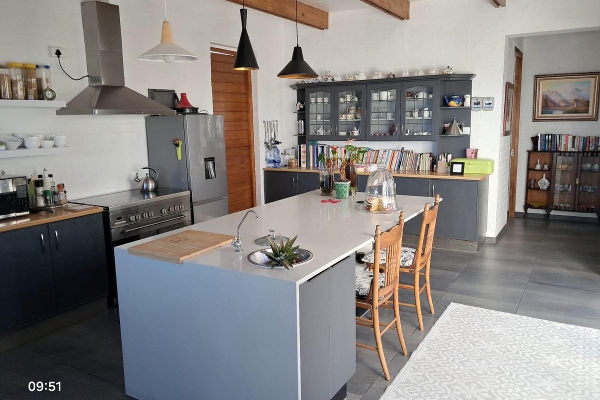 Modern kitchen featuring a central island with a prep sink, stainless steel range cooker, extractor fan, and ample dark grey cabinetry with glass-fronted display units.