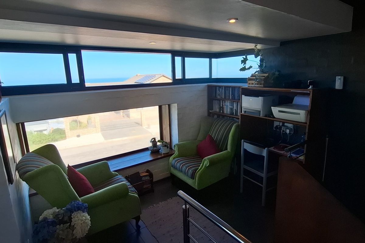 A cozy seating area featuring large horizontal windows that provide natural light and views of the surrounding neighborhood and ocean.