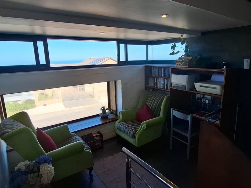 A cozy seating area featuring large horizontal windows that provide natural light and views of the surrounding neighborhood and ocean.