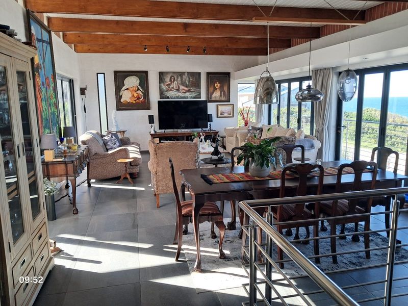 Spacious open-plan living and dining area featuring exposed timber ceiling beams, large glass sliding doors, and modern floor tiling with scenic views.