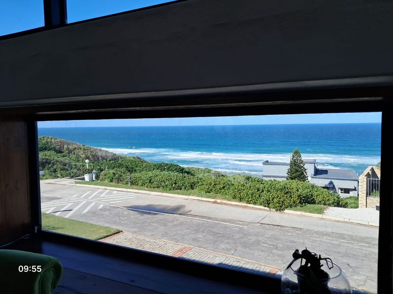 A scenic view of the ocean and coastal landscape captured through a large window, highlighting the property's prime location.