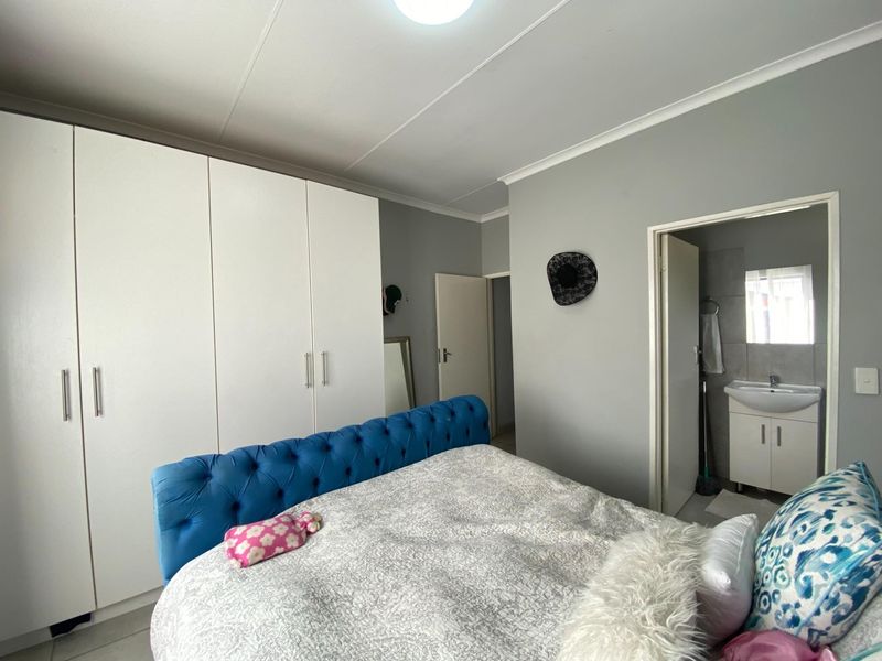 A well-maintained bedroom featuring built-in cupboards, neutral wall finishes, and direct access to an en-suite bathroom.