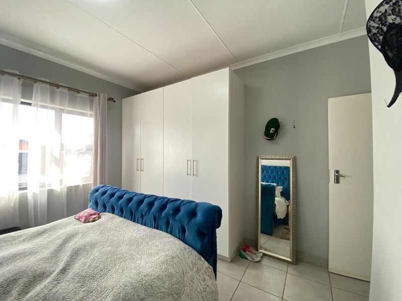 A functional bedroom featuring built-in cupboards, tiled flooring, and a coved ceiling, providing a clean and practical living space.