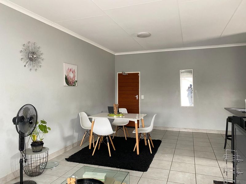Open plan living and dining area featuring neutral grey walls, tiled flooring, and a functional layout suitable for modern living.