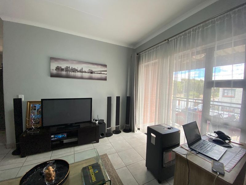A bright living room featuring tiled flooring and a large sliding glass door that provides access to an outdoor balcony area.