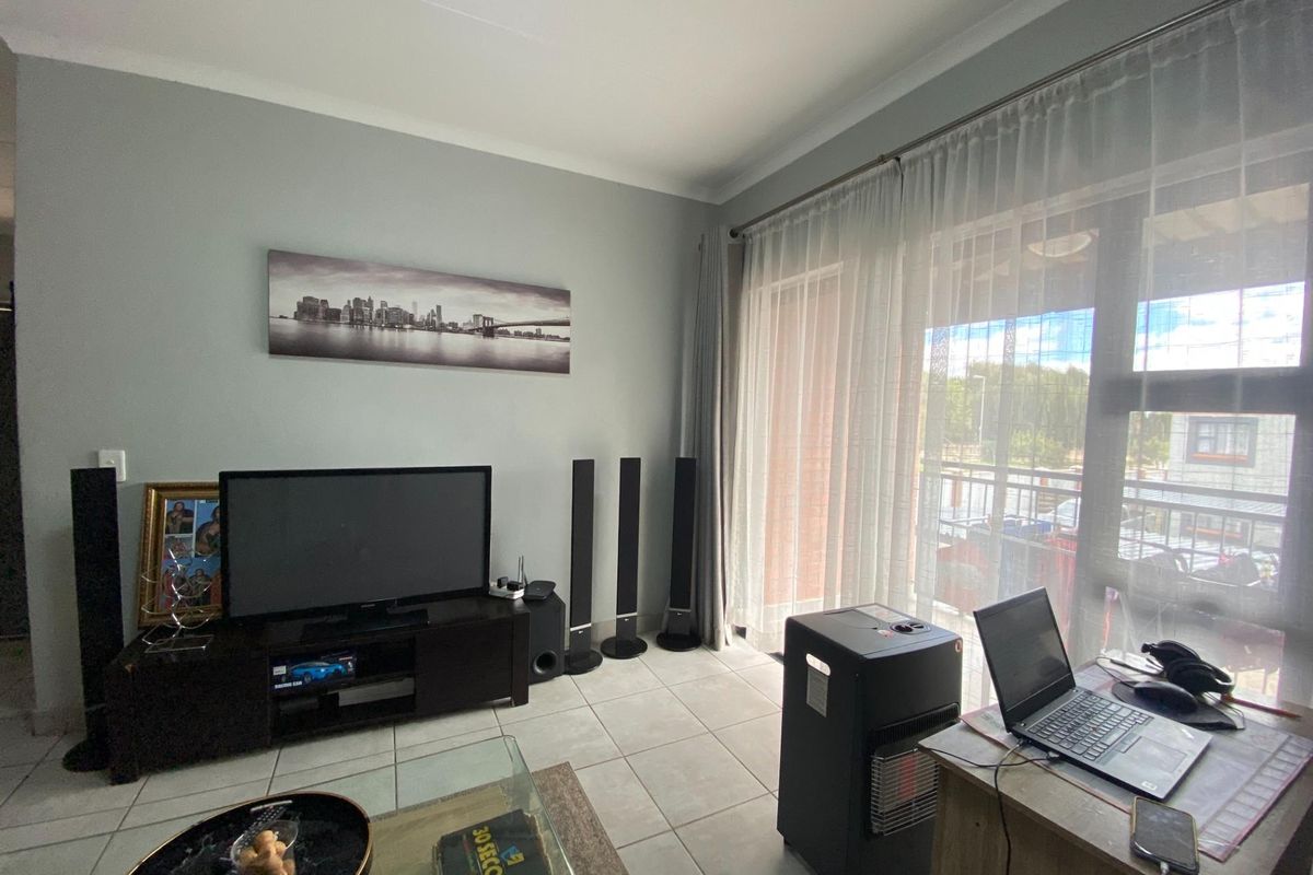 A bright living room featuring tiled flooring and a large sliding glass door that provides access to an outdoor balcony area.