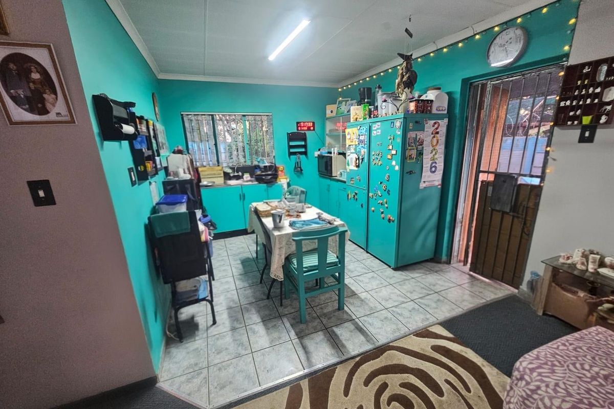 A functional kitchen area featuring tiled flooring, built-in cabinetry, and direct access to an exterior door with security gate.