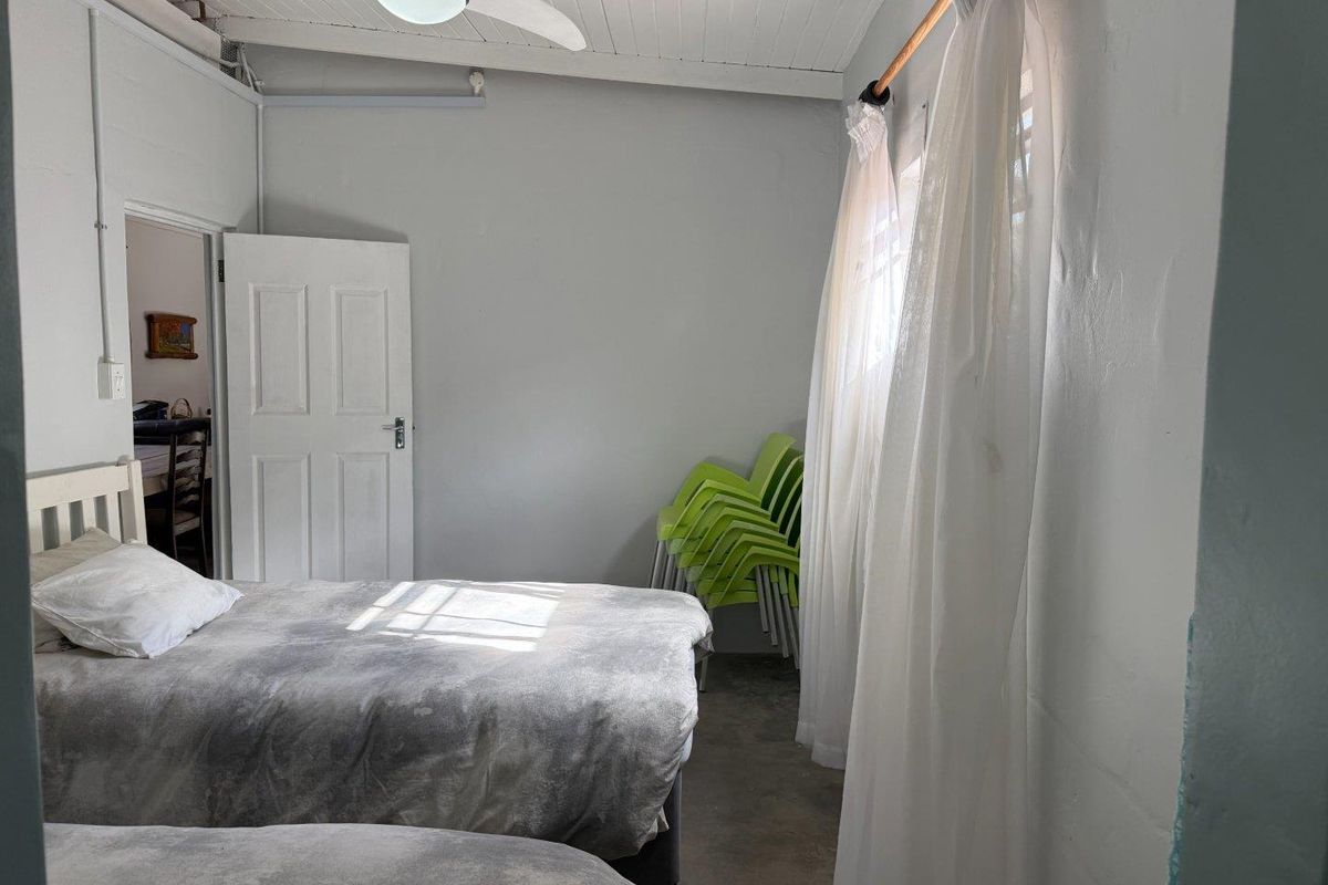 A functional bedroom featuring a white timber-paneled ceiling with a mounted ceiling fan and a standard interior door.