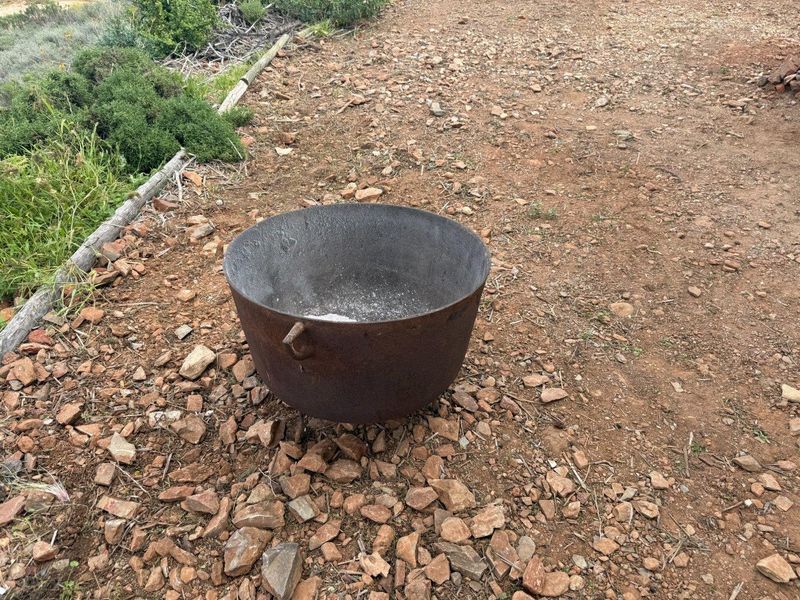 An outdoor area featuring a rustic cast iron fire pit set on a rocky, natural ground surface.