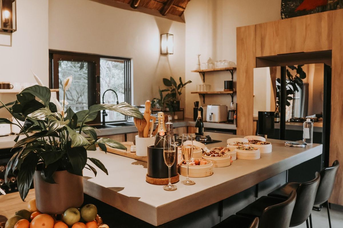 Modern kitchen featuring a large central island with stone countertop, dark cabinetry, and open shelving, creating a warm and inviting culinary space.