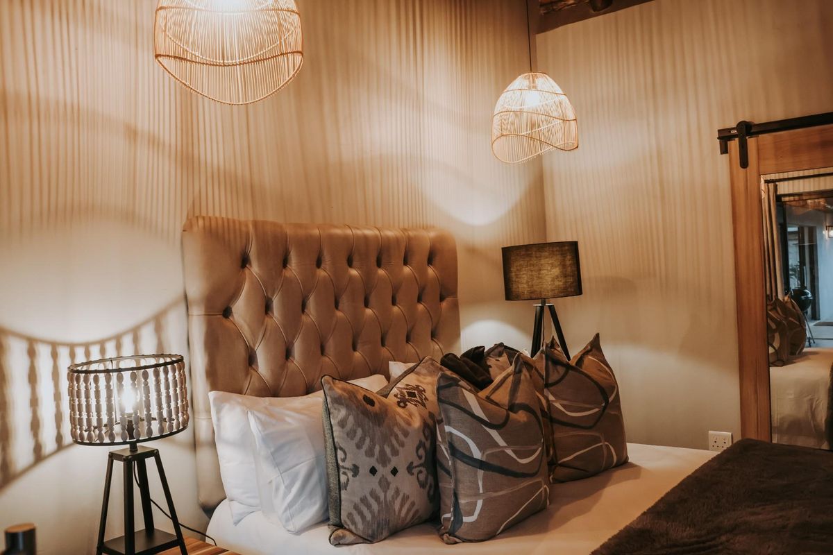 A cozy bedroom featuring a tufted headboard, warm ambient lighting, and a sliding barn-style door.
