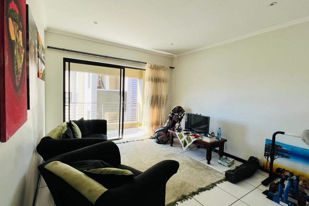 A bright living room featuring tiled flooring, recessed ceiling lighting, and large sliding glass doors that open onto a private balcony.