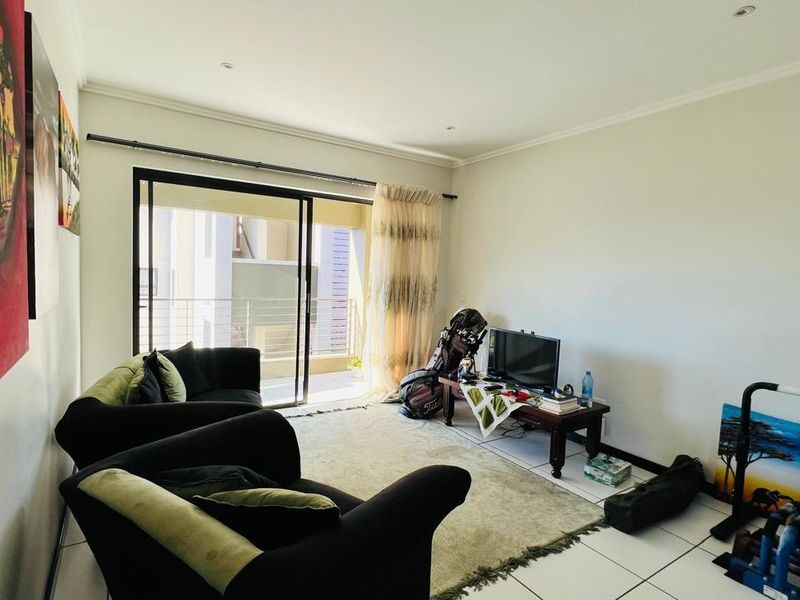 A bright living room featuring tiled flooring, recessed ceiling lighting, and large sliding glass doors that open onto a private balcony.
