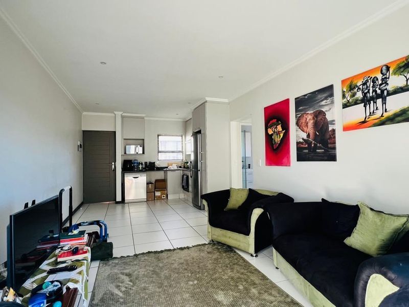 Open-plan living area featuring tiled flooring and a compact kitchen with built-in cabinetry and integrated appliances.