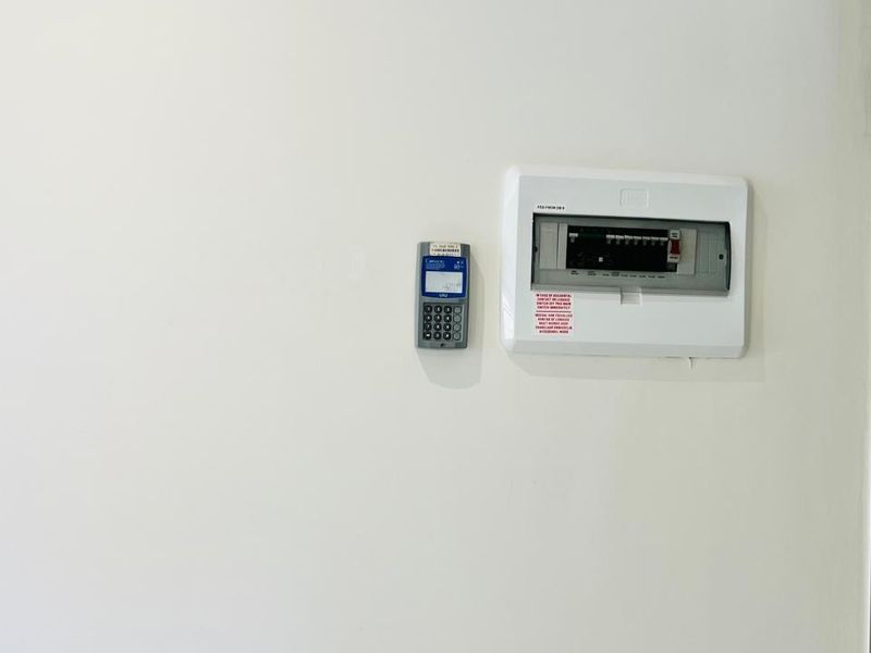 A clean interior wall featuring a mounted electrical distribution board and a digital utility meter.