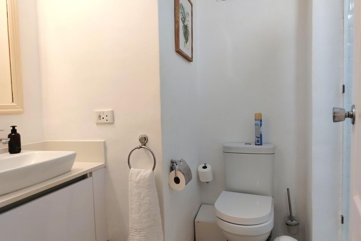 A functional bathroom featuring a white vanity with a vessel sink, a standard toilet, and a small high-level window for ventilation.