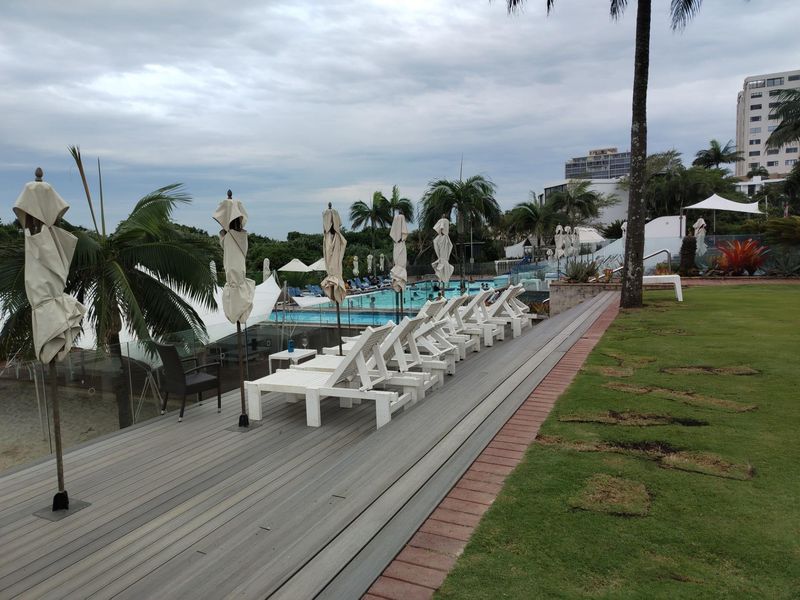 A well-maintained outdoor pool area featuring a timber deck, glass balustrades, and landscaped lawn, providing a communal recreational space for residents.