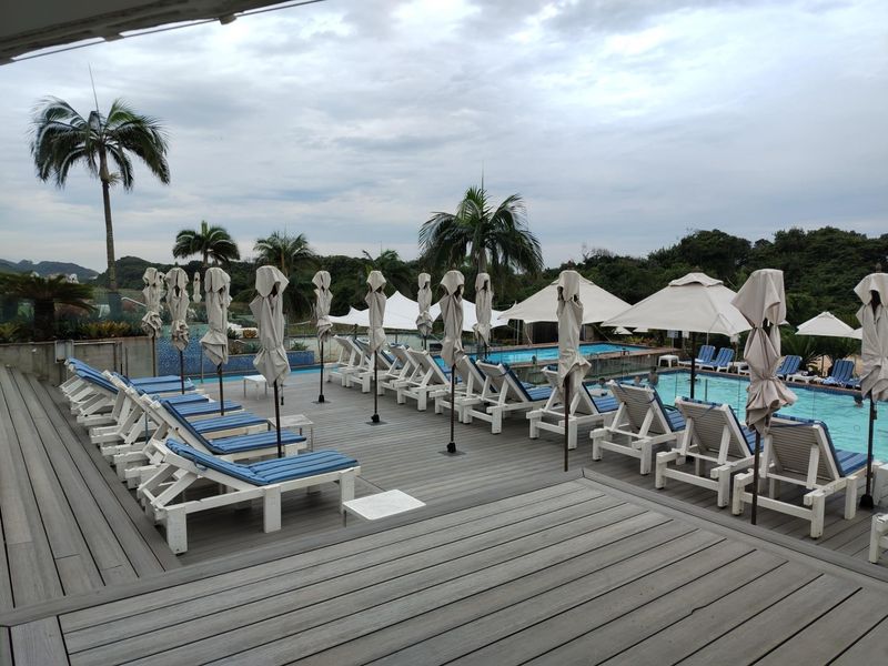 A well-maintained outdoor pool area featuring a spacious composite timber deck, glass balustrades, and integrated swimming pool facilities.